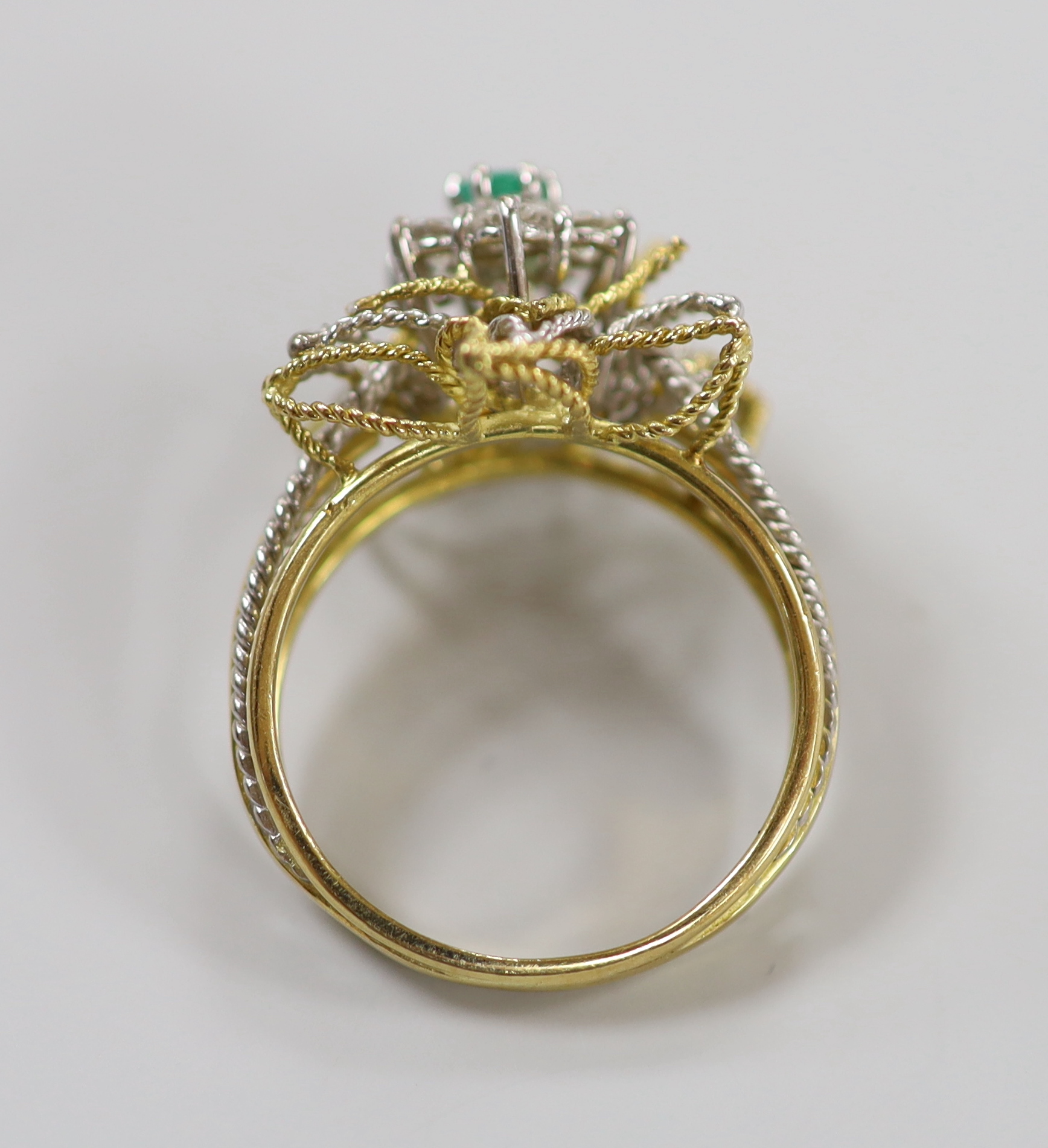 A yellow and white metal, emerald and diamond cluster set stylised flower head ring, size P, gross weight 6.3 grams.